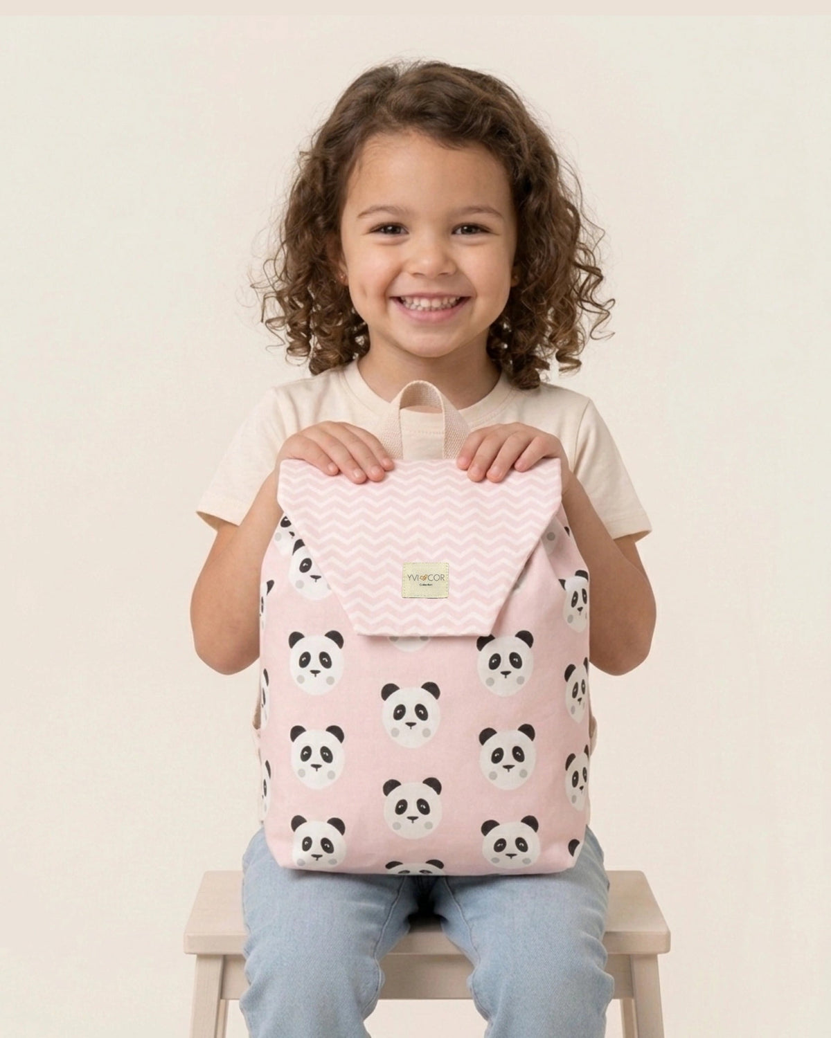 Niña sujetando una mochila infantil rosa con estampado de pandas