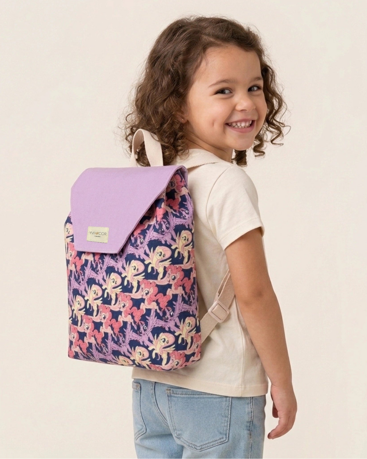 Niña llevando una mochila infantil lila con estampado de ponis y solapa lila