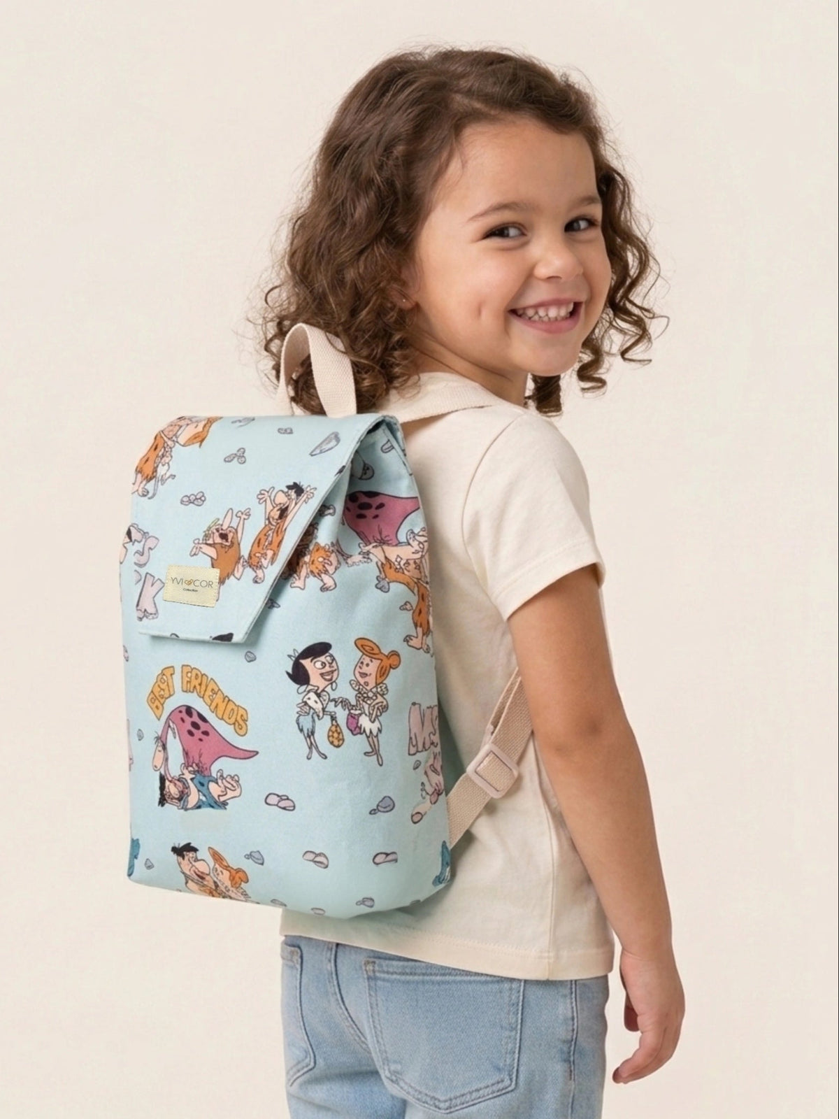 Vista frontal de una mochila infantil azul claro con estampado de personajes prehistóricos