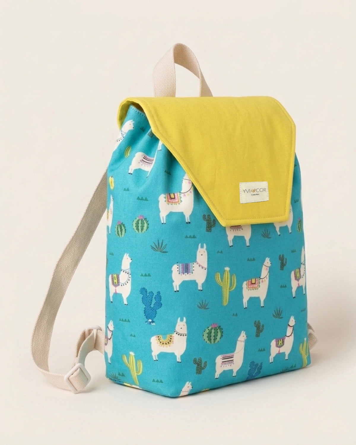 Niña sujetando una mochila infantil turquesa con estampado de llamas y cactus
