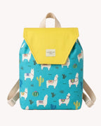 Niña llevando una mochila infantil turquesa con estampado de llamas y cactus